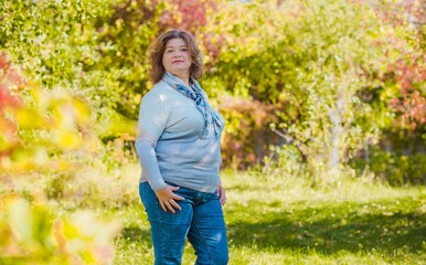 Portrait of attractive plus size mature woman in casual style walk at city at good sunny autumn day and thinking about something. Life of women after 40-50 years