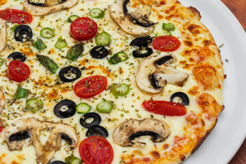 Vegetarian pizza on white plate. Mushrooms, cheese, black olives and tomatoes cherry.