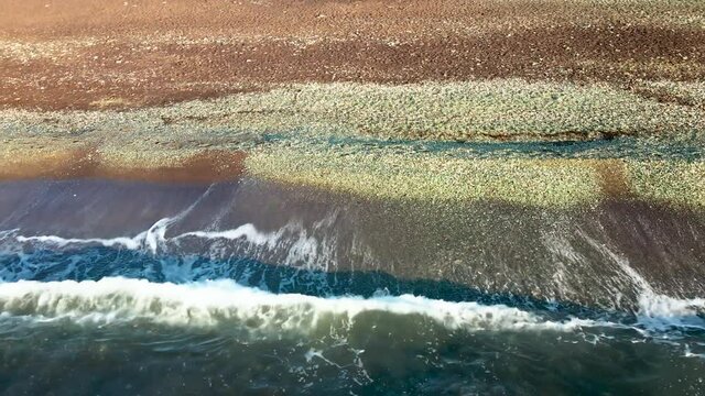 Glass bays in Vladivostok. View from above. Close-up. The camera pans over the edge of a glass beach washed by waves.