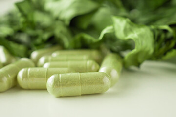 Herbal medicine capsules with Andrographis paniculata leaf on white background