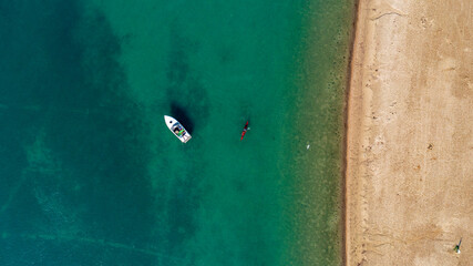 Overhead aerial view of a fisherman, a kayaker and a flying seagull at Belle Isle Beach. 