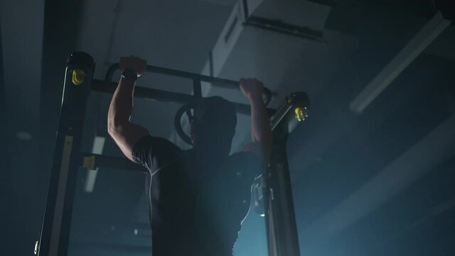 Disabled athlete in wheelchair performs pull-ups on the horizontal bar, gym training and physical activity, people with disabilities, 4k slow motion.