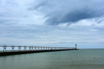 Fototapeta na wymiar the historic manistee north pierhead lighthouse on fifth avenue beach on eastern lake michigan, michigan, with its elevated walkway, on a stormy day