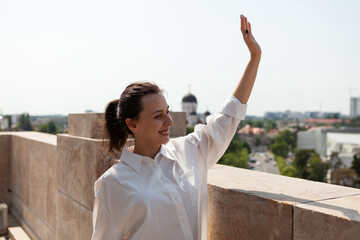 Woman toursit greeting people while standing on tower terrace enjoying panoramic view of metropolitan city. Landscape with urban skyscraper rooftop and aerial view from observation point