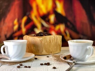 There are white coffee cups and gingerbread cookies on a wooden table by the fireplace