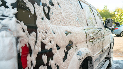 self-service car wash, black jeep is washed with foam and water
