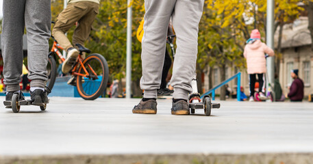 young boys ride on the sports field, on scooters and skates. street sports.