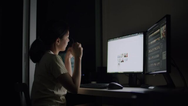 Asian woman work late at night and feel sleepy at the desk in a darkroom at home.