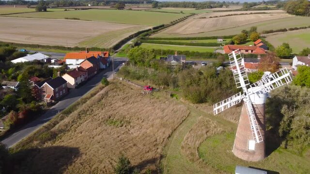 Billingford Windmill at farmland area with house and roads in Diss, Norfolk - aerial drone flying tracking shot