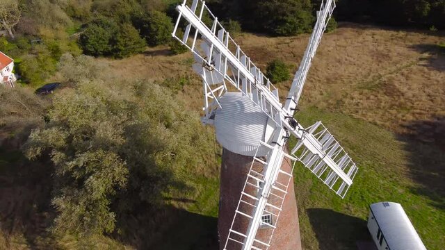 Billingford Windmill at a farm field area with house in Diss, Norfolk - aerial drone flying tracking shot