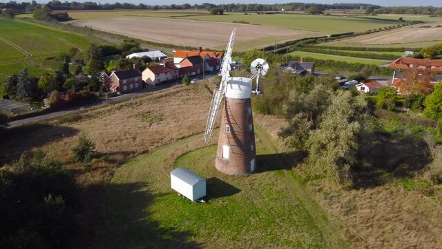 Billingford Windmill at farmland area with house and roads in Diss, Norfolk - aerial drone rotation tracking shot
