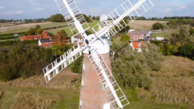 Billingford Windmill at road side field area with house in Diss, Norfolk - aerial drone flying shot