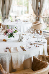 Table setting on the veranda. transparent glasses and white plates on a tablecloth against a background of greenery. Wedding day and holiday atmosphere.