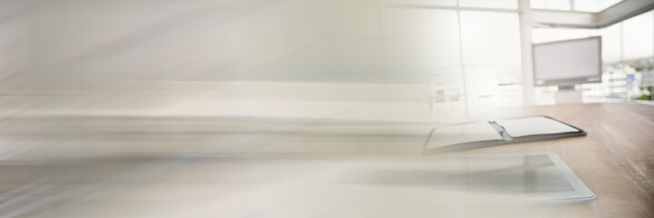 Digital tablet computer with open diary on desk in bright empty office by blurred effect