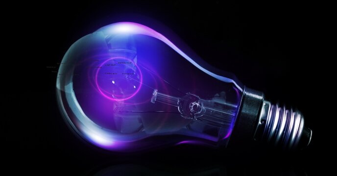 Digitally generated image of glowing purple light bulb against black background