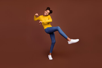 Fototapeta na wymiar Full size photo of small girl do sport wear sweater jeans shoes isolated on brown color background
