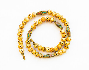 top view of coiled vintage necklace from carved bone and inlaid brass beads on white paper