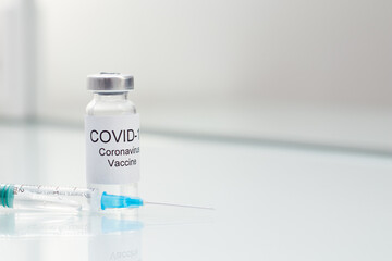 COVID 19 Vial with coronavirus vaccine and syringe on white glass table