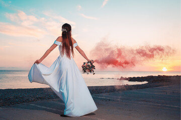 Bachelorette party on the ocean. A young bride is spinning in a white dress with a bouquet, against the background of the sunset. View from the back