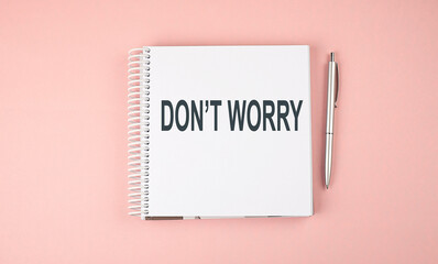 DON'T WORRY text on notebook with pen on the pink background