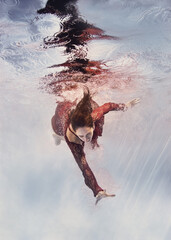 A girl in a red lace dress swims underwater as if flying on a light background