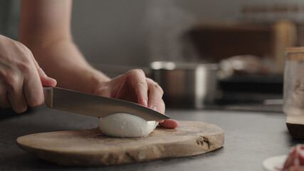 man slicing mozzarella on olive board