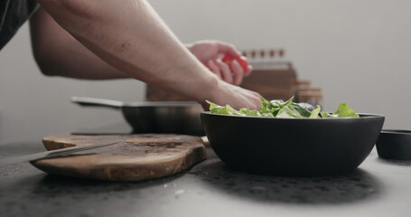 man cut cherry tomato for salad on kitchen countertop