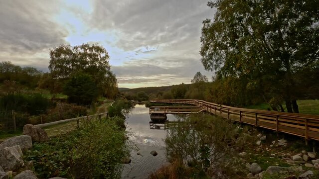 Traveling on the side of a wooden footbridge in Branda de Aveleda, Portugal with river and trees on a cloudy day, Parque Nacional da Peneda Geres, Portugal.