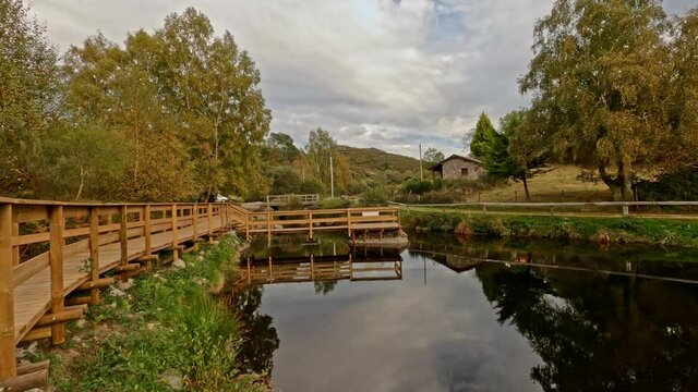 Travelling forward on the wooden footbridge of Branda de Aveleda, Portugal with trees and river on a cloudy day, Parque Nacional da Peneda Geres, Portugal.