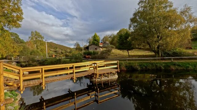 Traveling forward on the wooden footbridge of Branda de Aveleda, Portugal with trees and river with beautiful sunset light, Parque Nacional da Peneda Geres, Portugal.