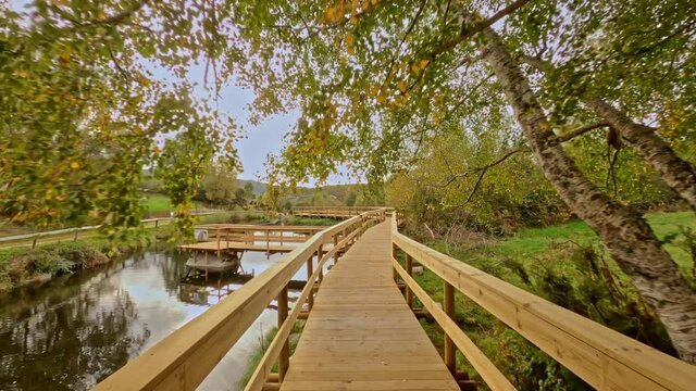 Travelling forward from a wooden footbridge in Branda de Aveleda, Portugal with river and trees on a cloudy day, Parque Nacional da Peneda Geres, Portugal.