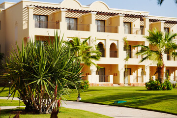Holiday resort. Luxury Egyptian hotel with palm trees, perfect green lawn and clear blue sky.
