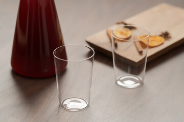 Mulled wine in glass carafe and tumbler glasses on walnut table