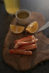 Obraz na płótnie Canvas Crab legs with lemon and dressing on olive woob board