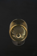 White wine in a wineglass on black oak table with copy space
