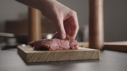 Man seasoning steak with salt and pepper and rolling it over on wood board