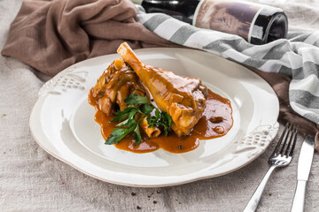 Braised lamb shank meat with gravy on white plate on the table