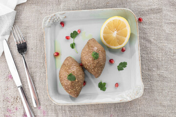 Minced meat patty with lemon on the plate on the table