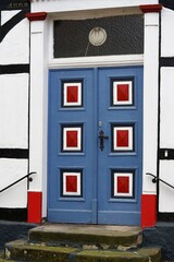 an old door in blue red and black on a historic house,tür, architektur, bauwerk, haus, alt, fenster, eingang, wand, rot, front, zuhause, holz, fassade, backstein, äusseres, hölzern, blau, strasse, 