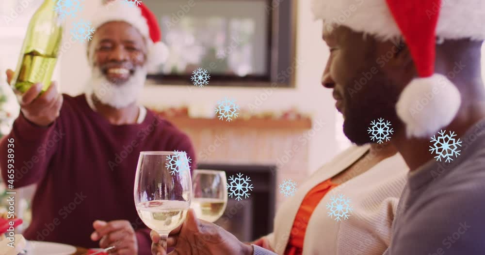 Wall mural Animation of snow falling over happy african american family wearing santa hats and having dinner