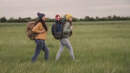 Happy girls travel with backpacks hiking, fun weekend outing with travel bags, active outdoor lifestyle, female group recreation, hipster travelers for thousands of years, free movement in search of