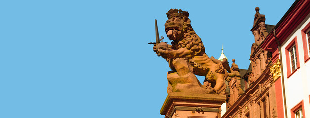 Banner with statue of lion king with a sword and crone at University Square, Heidelberg, Germany, at blue sky solid background with copy space. Concept of historical heritage. - obrazy, fototapety, plakaty