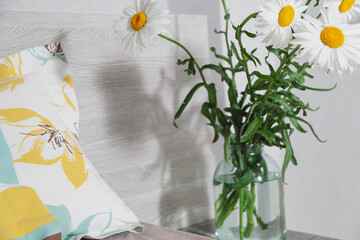 Daisies in vase on bedside table