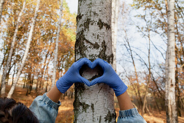 Hands in gloves folded of heart on birch background
