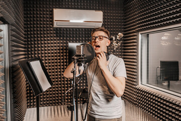 The vocalist sings in the studio in a microphone. Man in headphones writes a podcast, an audiobook. Artist, recording an album, working with the label. Announcer records a speech at a radio station