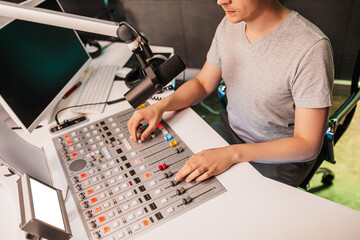 Sound producer works on a mixing desk. The DJ hosts the program and communicates with the audience...
