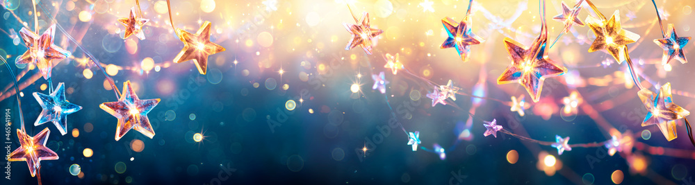 Wall mural christmas stars with golden lights hanging in blue background - string with abstract defocused bokeh
