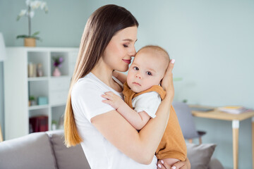 Photo of pretty sweet lady wear white t-shirt smiling holding arms hands kissing baby inside...