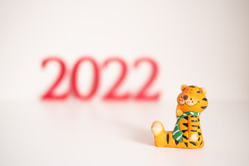 Red number 2022 and figurine of tiger on white background. Funny tiger symbol of the Chinese New Year 2022. High quality photo