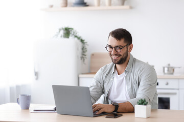 Happy handsome mature european male teacher or businessman with beard in glasses working at laptop